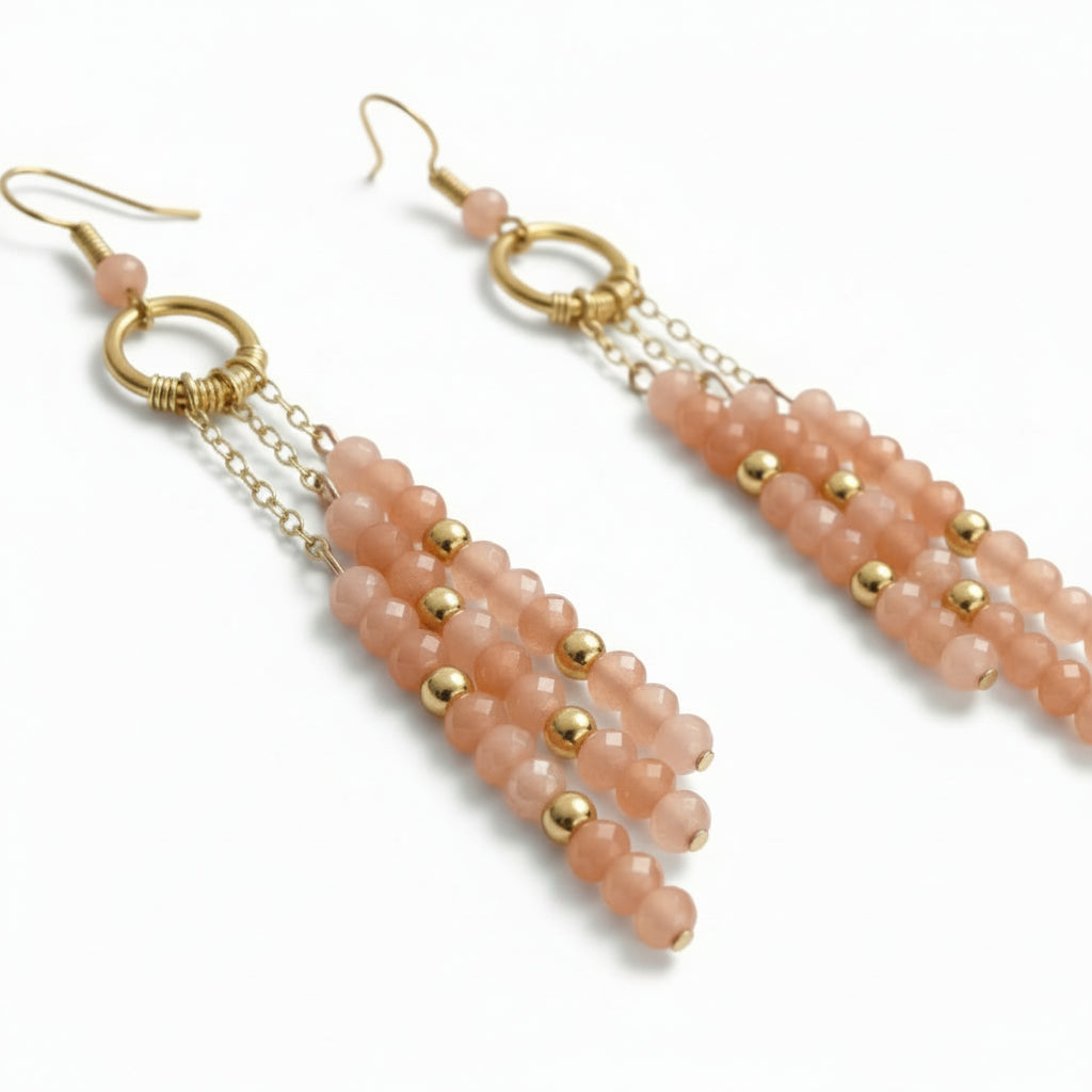 Pair of pink beaded earrings with gold accents on a white background