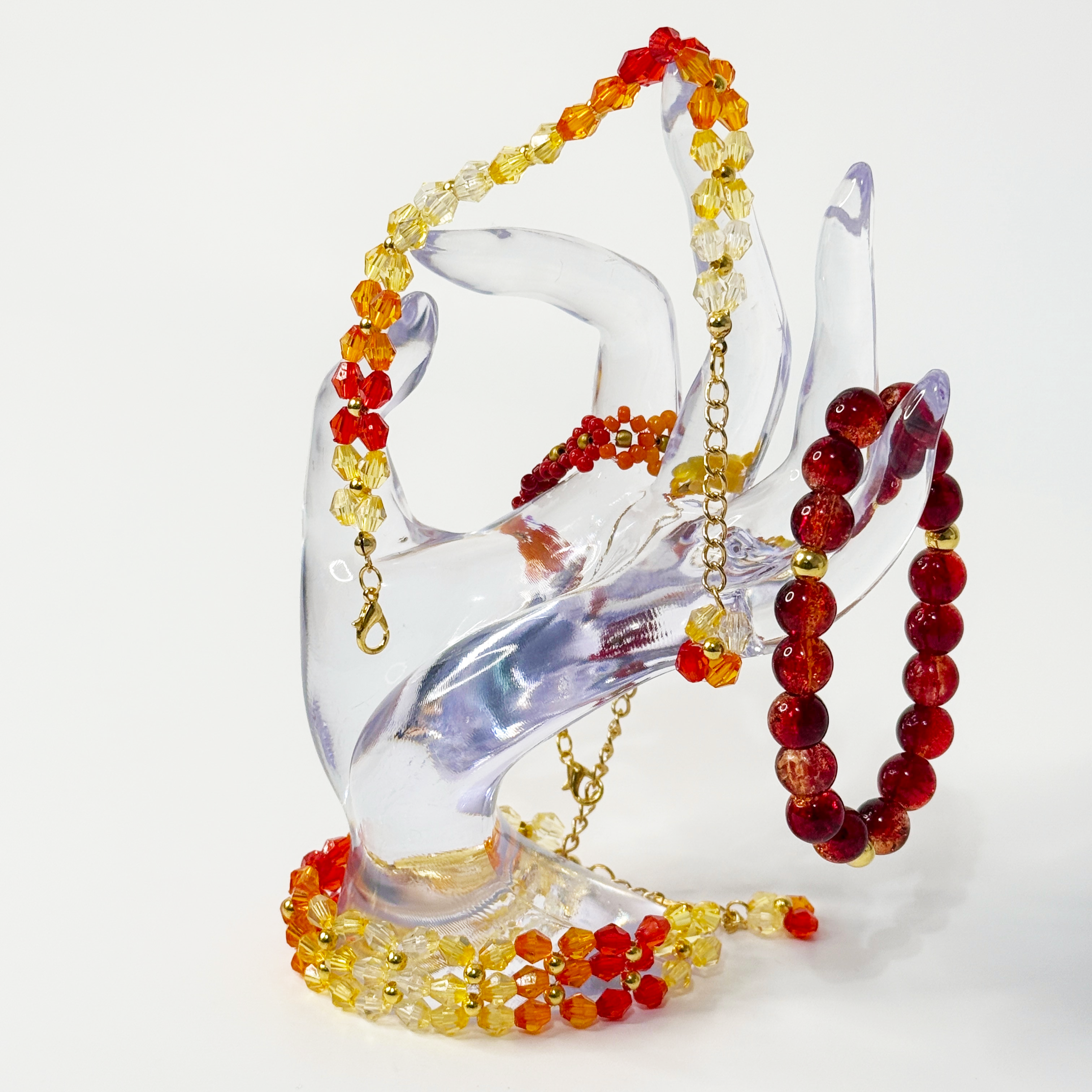 Colorful beaded bracelets on a clear hand-shaped stand against a white background