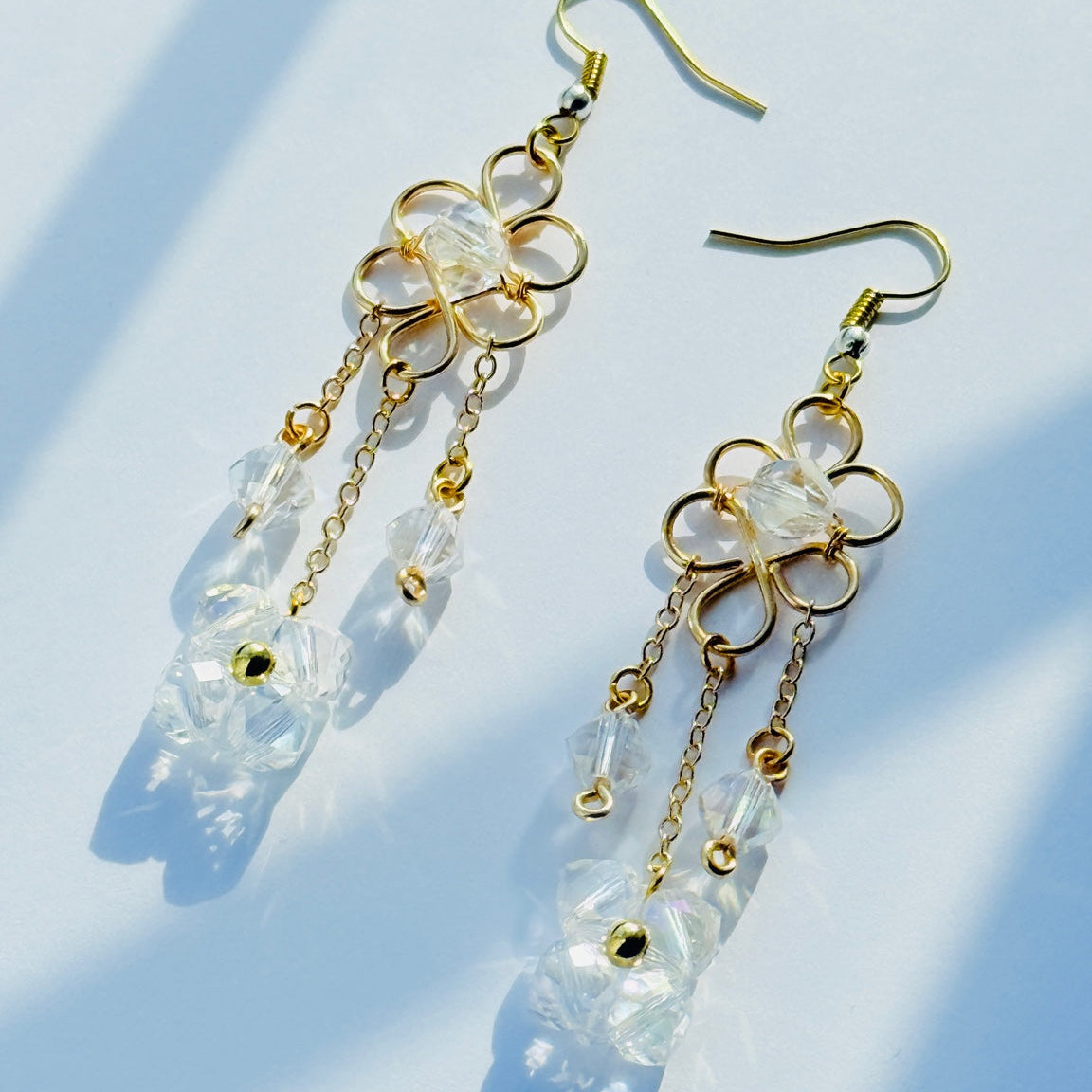 Gold and clear crystal earrings on a light blue background