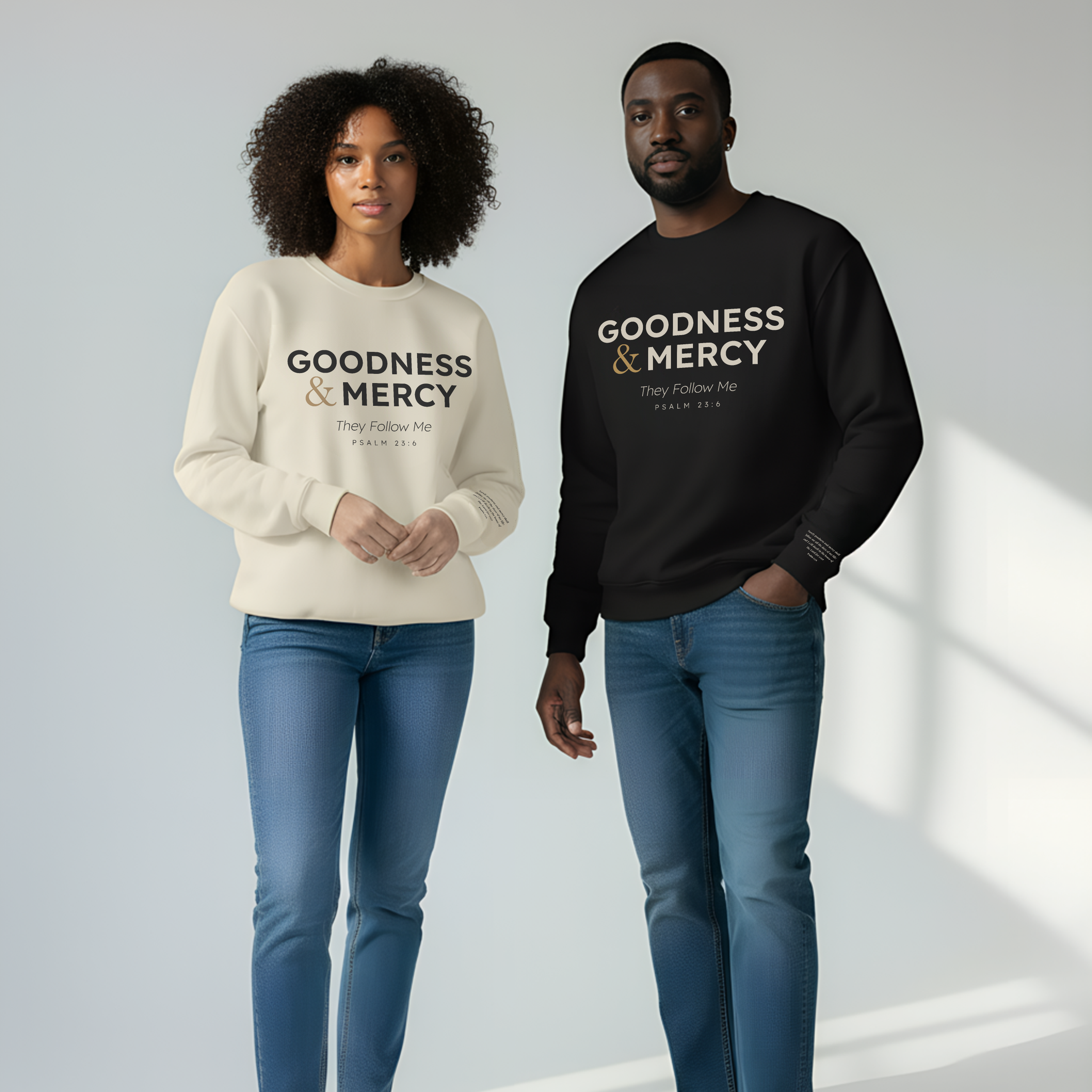 Two people wearing 'Goodness & Mercy' sweatshirts standing against a white background