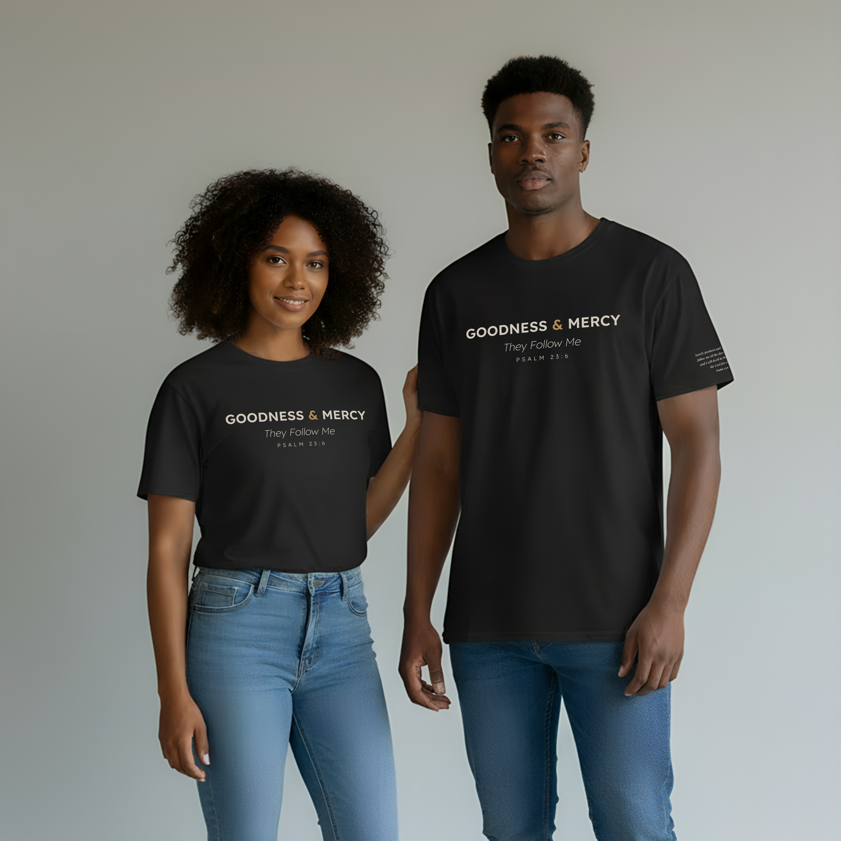 Two people wearing black t-shirts with 'Goodness & Mercy' text, standing side by side against a plain background.