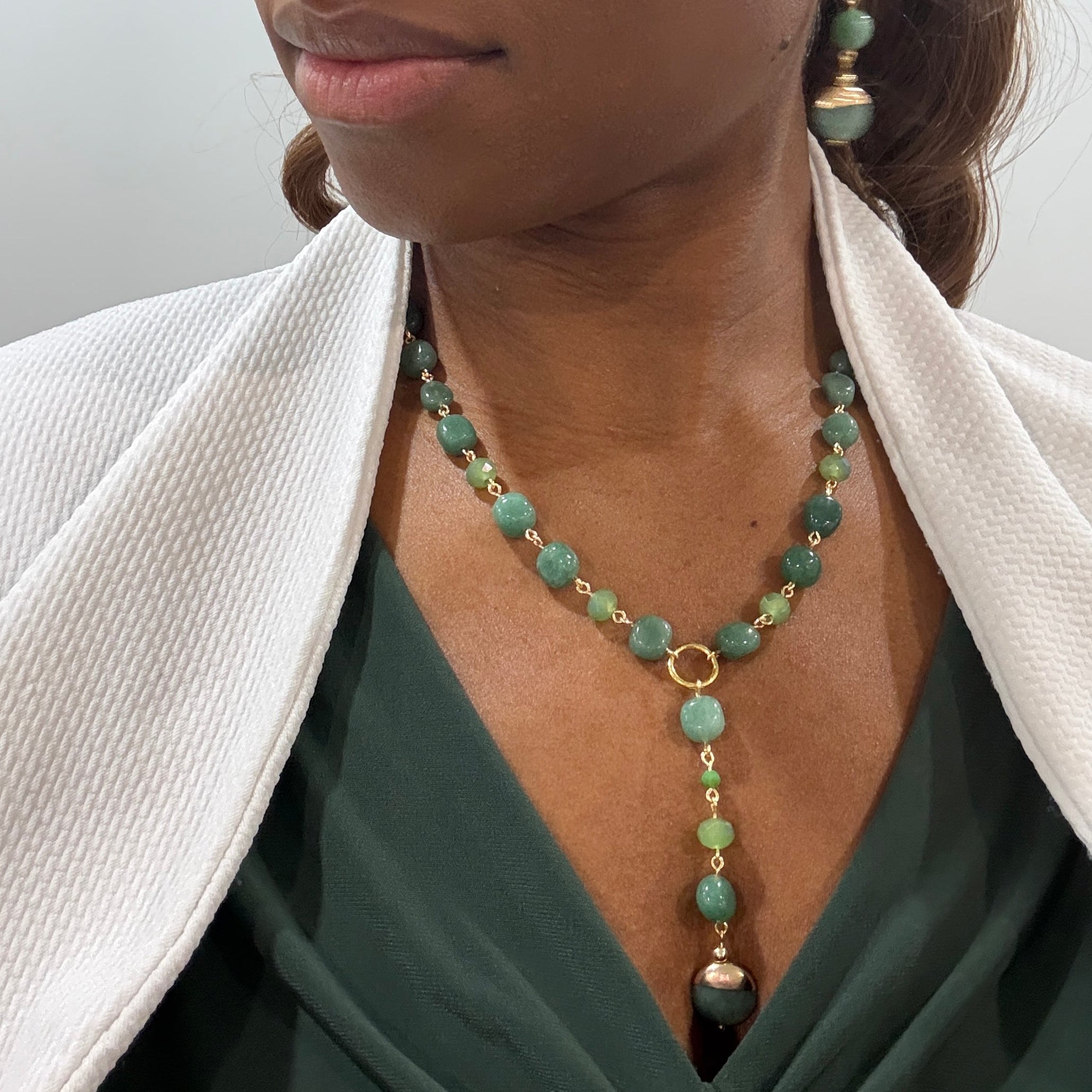 Close-up of a person wearing a green beaded necklace with a plain background