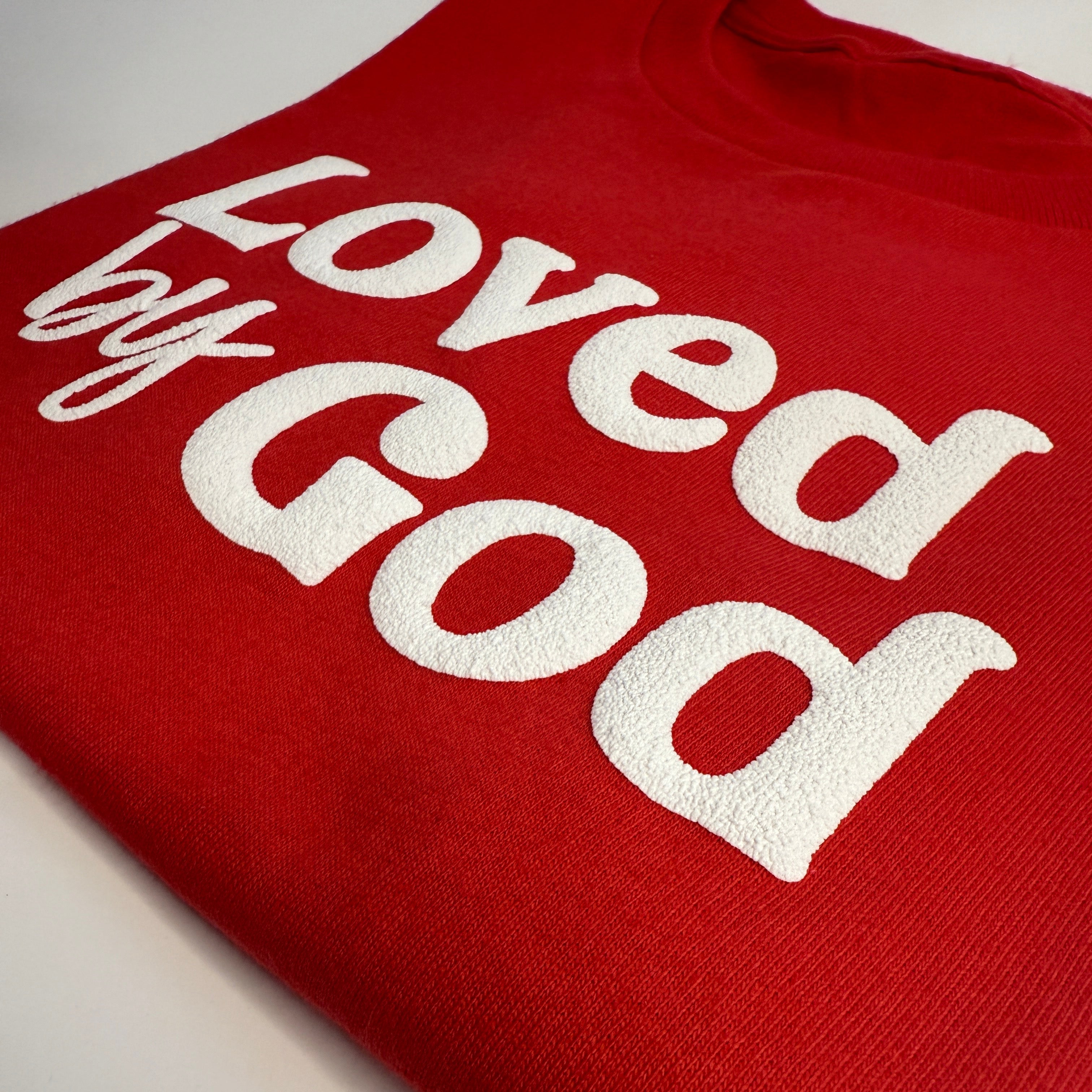 Red shirt with 'Loved by God' text on a white background