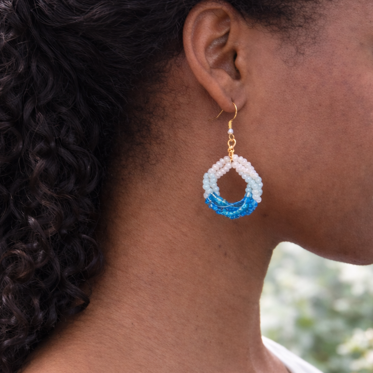 Woman wearing a blue and gold earring with a blurred natural background