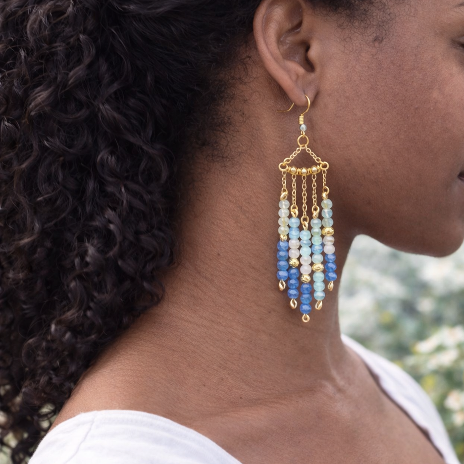 Close-up of a person wearing colorful beaded earrings with a blurred natural background