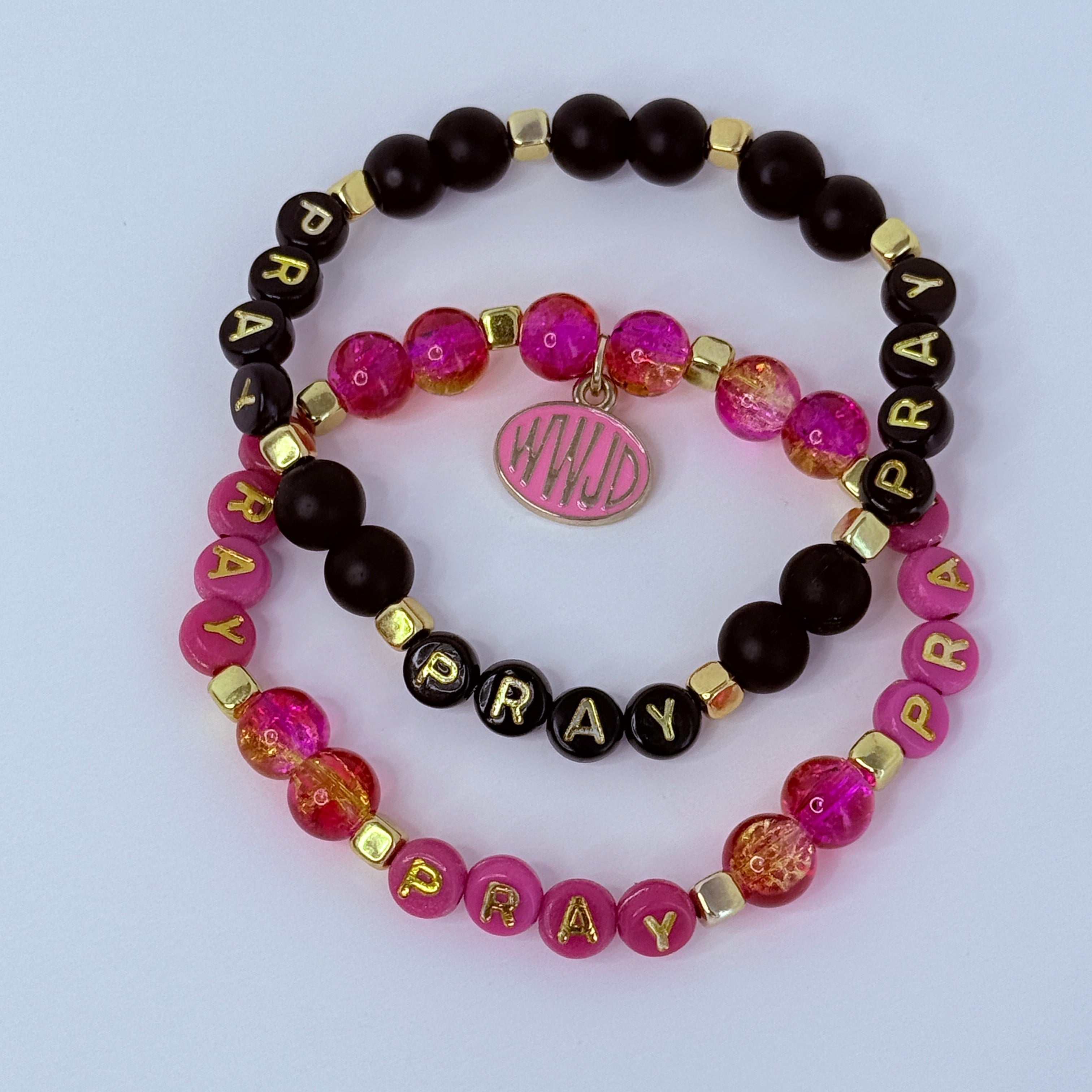 Three beaded bracelets with 'PRAY' beads on a light purple background