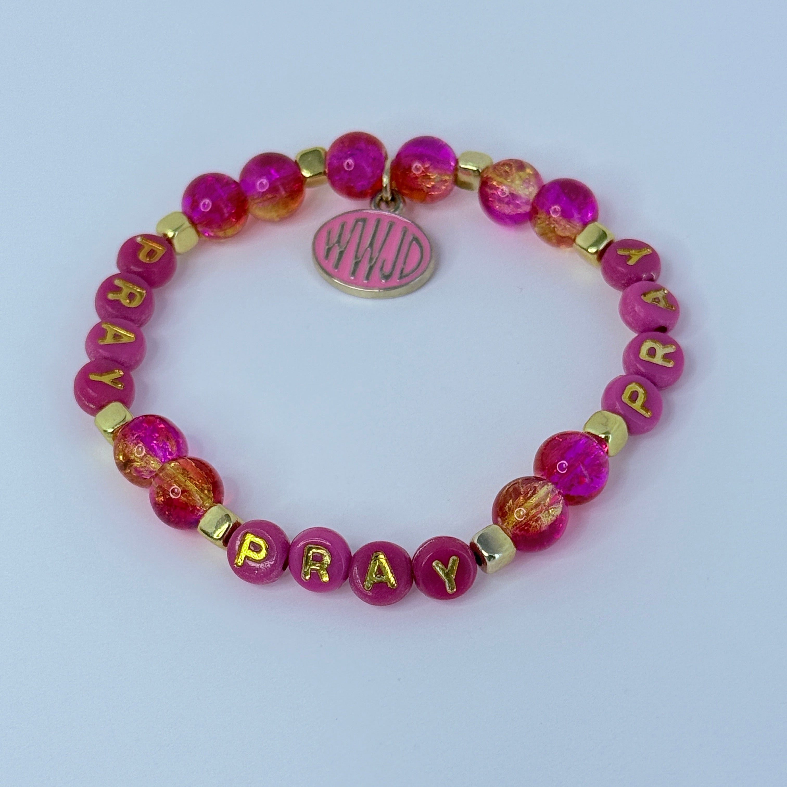Pink beaded bracelet with 'PRAY' letters on a light purple background