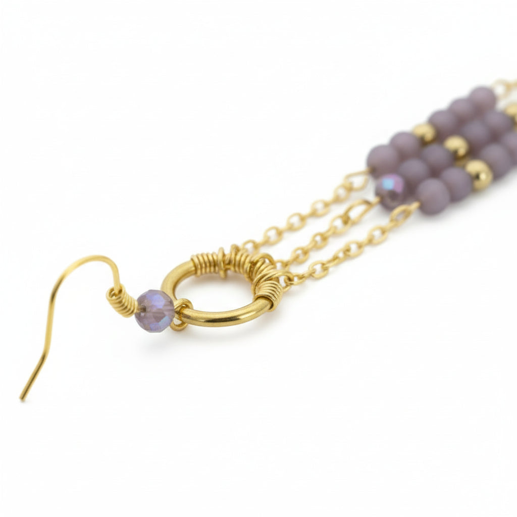 Gold earring with purple beads on a white background