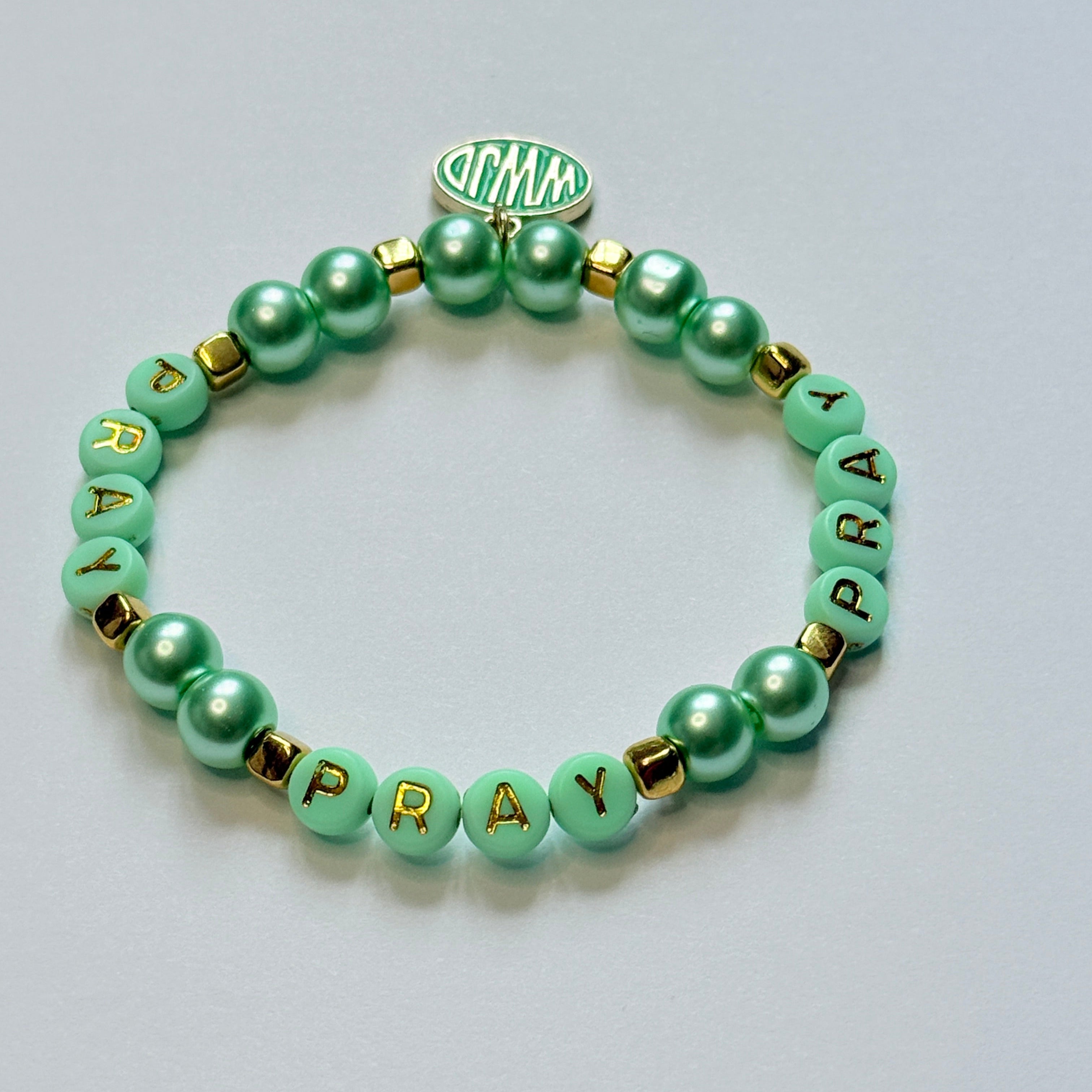 Green beaded bracelet with letter beads on a light gray background