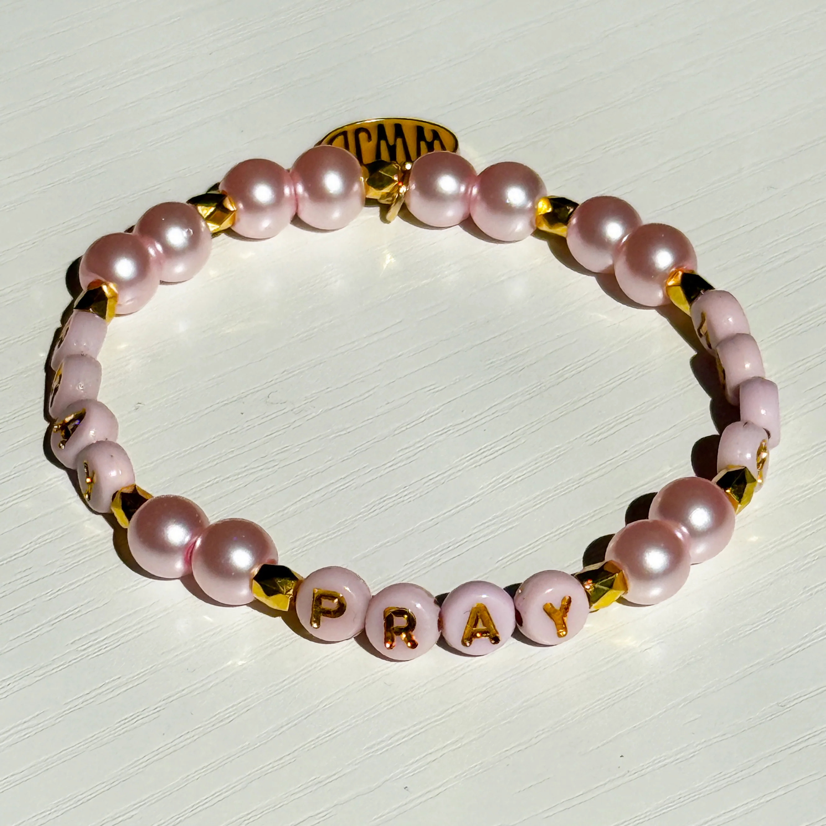 Bracelet with pink pearls and gold accents on a white background