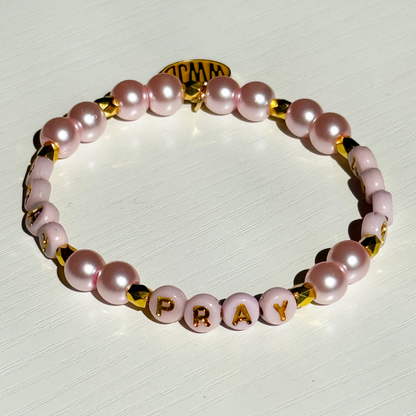 Bracelet with pink pearls and gold accents on a white background