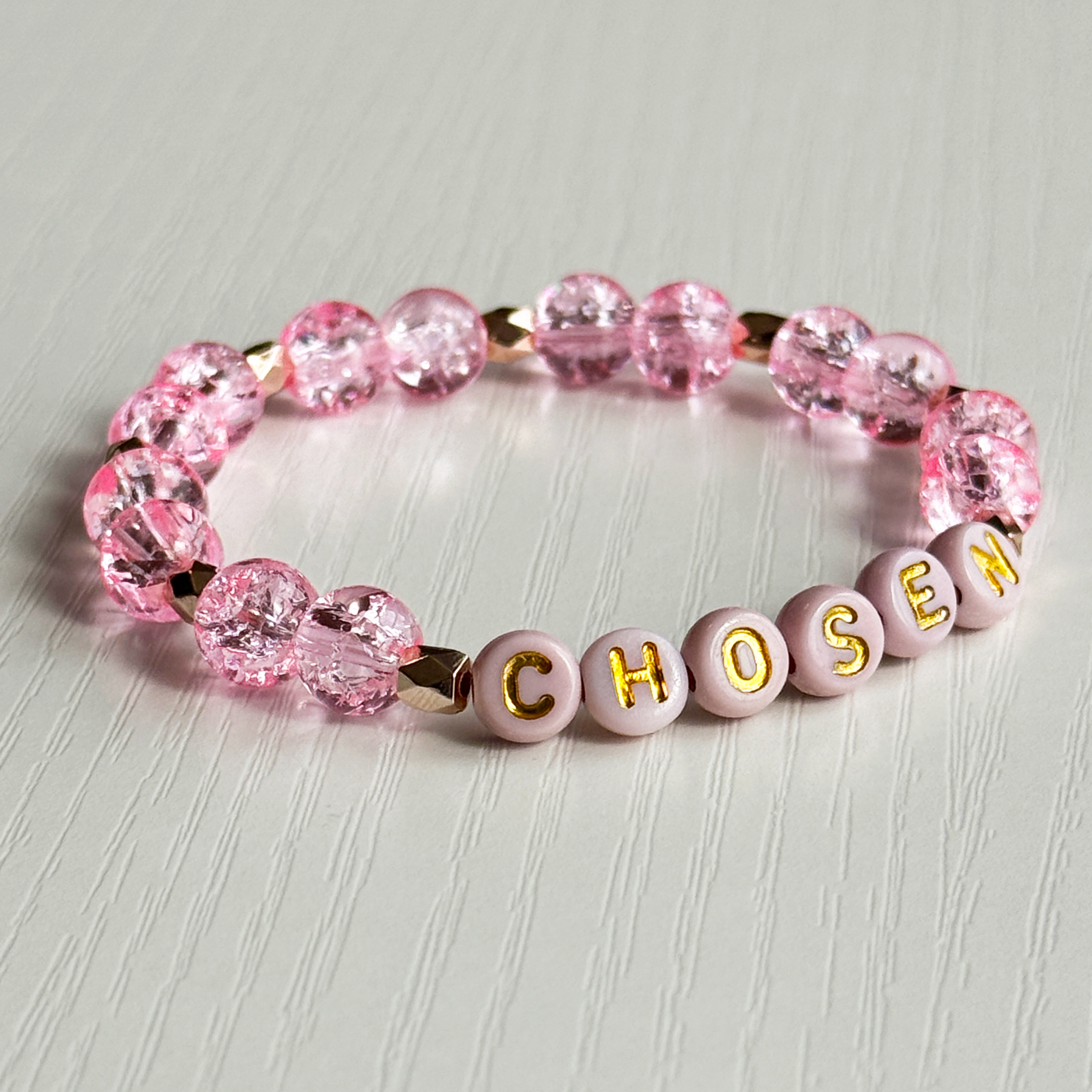 Pink beaded bracelet with 'CHOSEN' letters on a light gray background