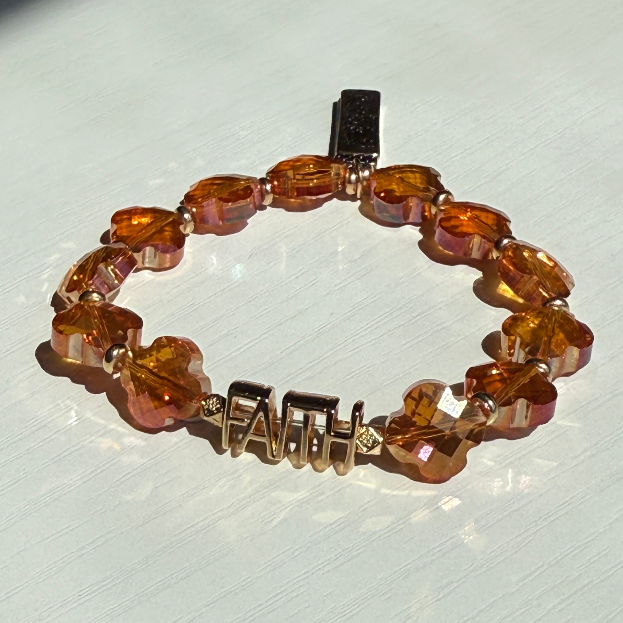 Beaded bracelet with amber-colored beads on a light gray background