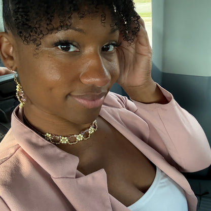 Woman wearing a pink hoodie and gold bracelet indoors