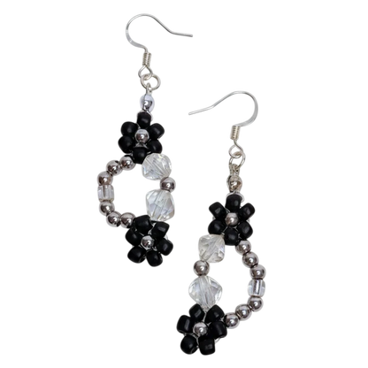 Pair of beaded earrings with black and white flowers on a white background