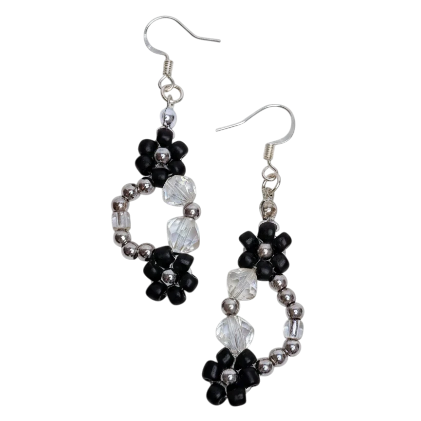 Pair of beaded earrings with black and white flowers on a white background