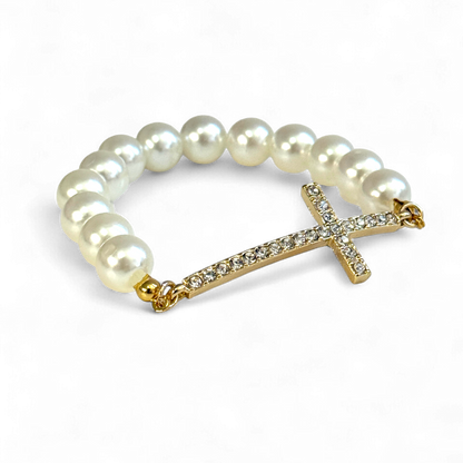 Pearl bracelet with a gold cross charm on a white background