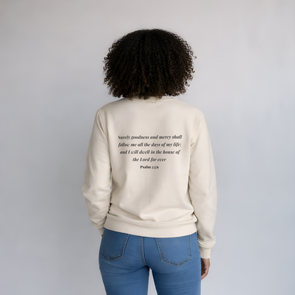 Person wearing a beige sweatshirt with text on the back, standing against a plain background