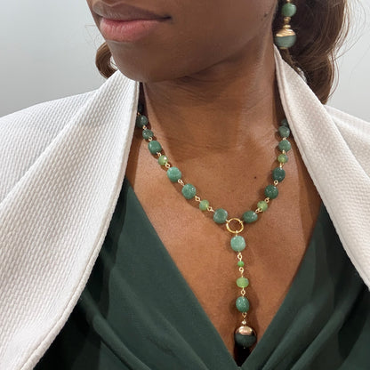 Close-up of a person wearing a green beaded necklace with a plain background