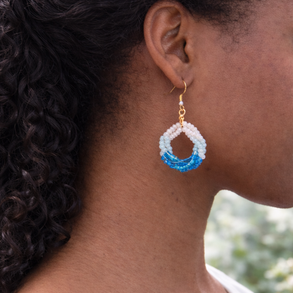 Woman wearing a blue and gold earring with a blurred natural background