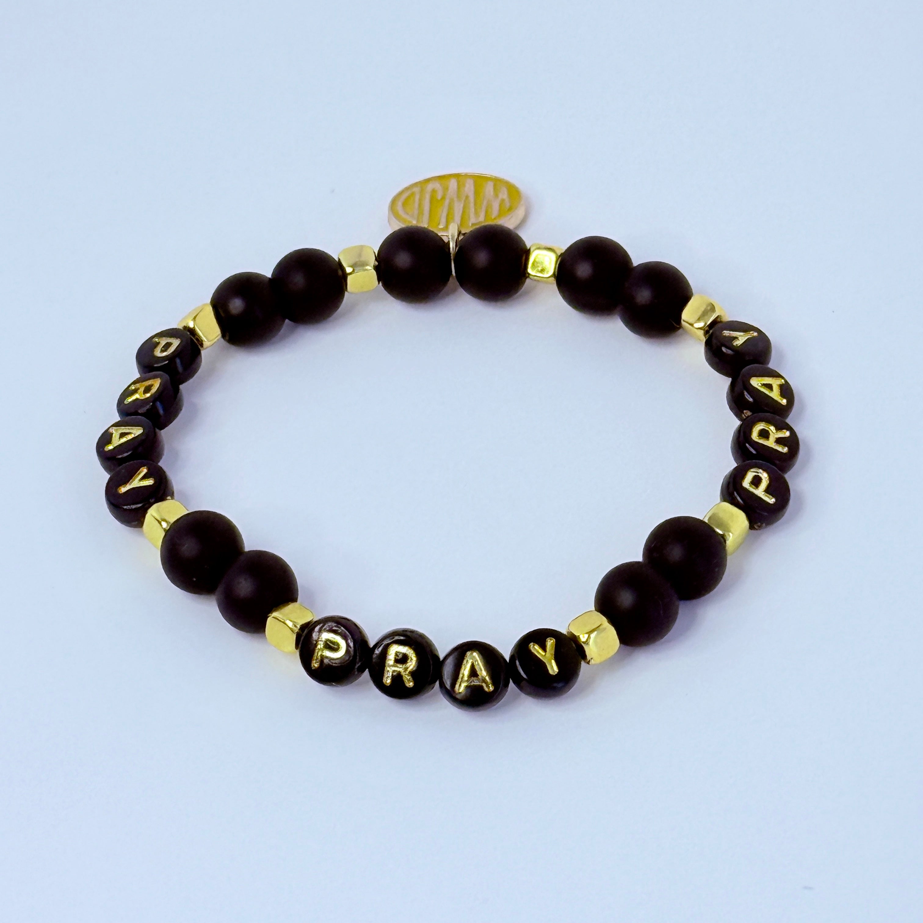 Black beaded bracelet with 'PRAY' beads on a light gray background