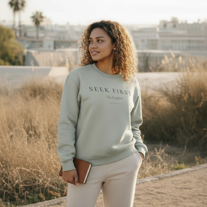 Woman wearing a light green sweatshirt with 'Seek First' text, standing outdoors.