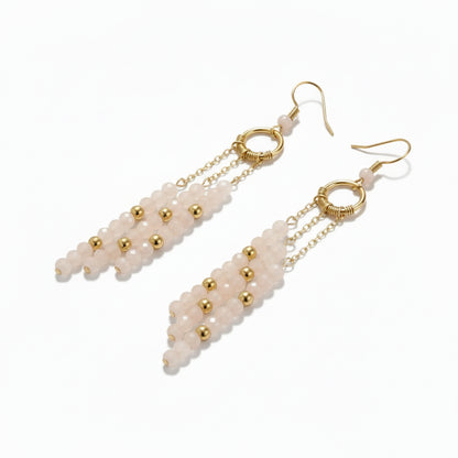 Pair of earrings with white beads and gold accents on a white background