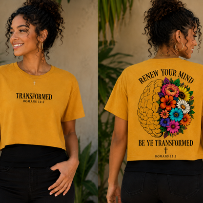 A woman modeling a mustard yellow graphic crop top, shown from both the front and back. The front features the text 'TRANSFORMED ROMANS 12:2' in black.