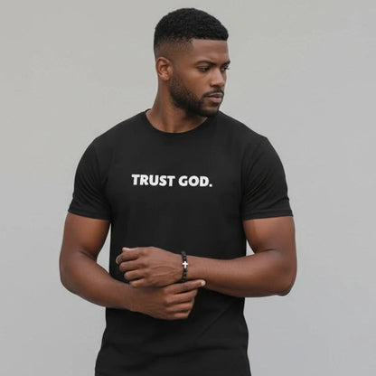 Man wearing a black t-shirt with 'TRUST GOD.' text against a gray background