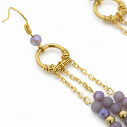 Gold earrings with purple beads on a white background