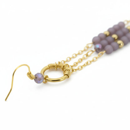 Gold earring with purple beads on a white background